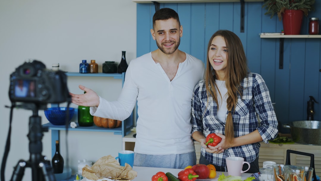 gallery-4 Young attractive couple recording video blog about vegetarian healthy food on dslr camera in the kitchen at home
