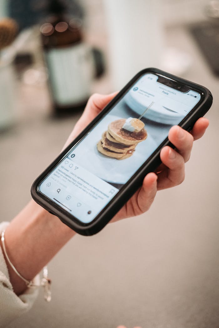 gallery-2 Hand holding a smartphone displaying a pancake recipe on a social media app.