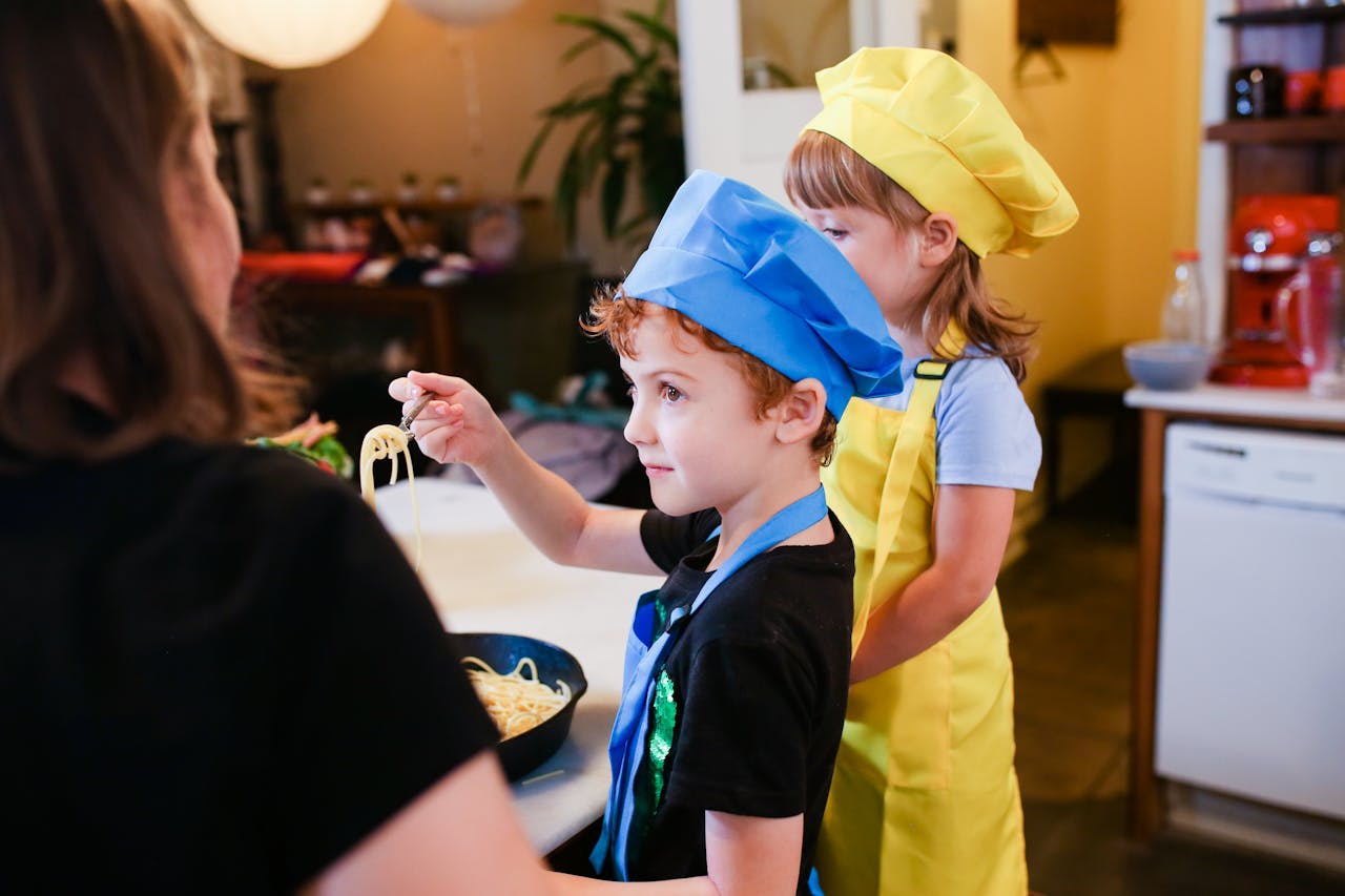 services-03 Children wearing chef hats cooking pasta in a lively kitchen setting. Inspiring young chefs.